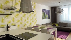 Eine moderne Küche mit einer zentralen Kochinsel, einem Essbereich mit Stühlen, einer Couch und einem violetten Teppich.