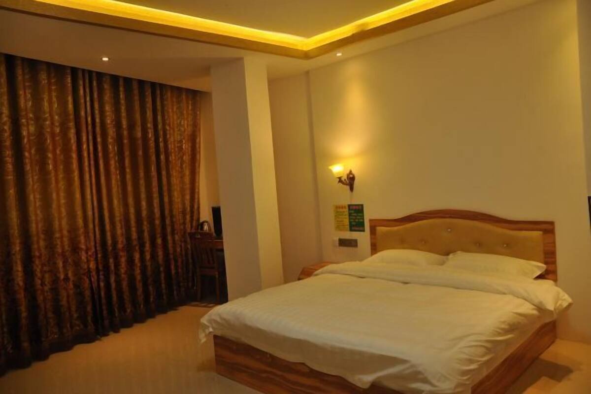 Une chambre à coucher avec un lit, une lampe fixée au mur et un rideau.
