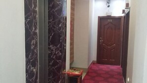 Un couloir avec un mur de marbre, une moquette rouge et une porte en bois portant le numéro 601.