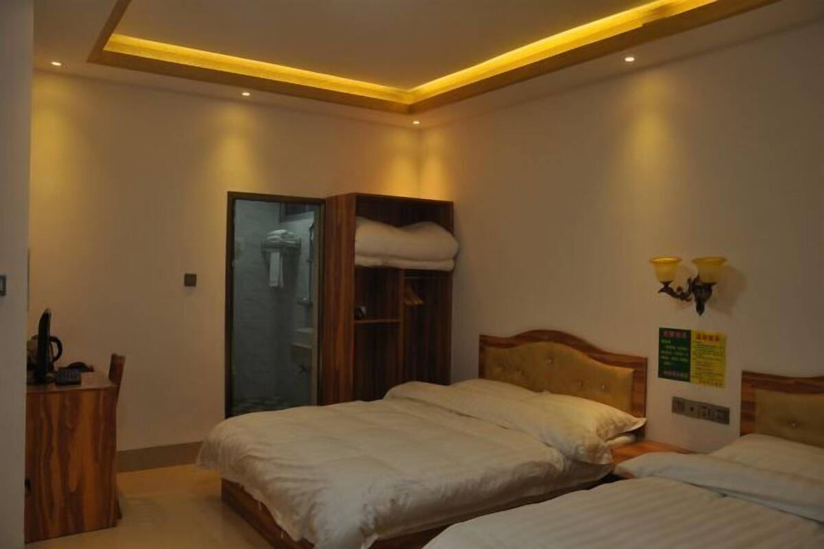 Une chambre d’hôtel avec deux lits, une armoire en bois, un bureau avec une chaise et un espace douche.