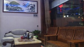 Une pièce comprenant un canapé, une chaise en bois, une petite table avec un plateau et un tableau encadré accroché au mur.