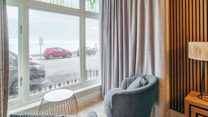 Ein Zimmer mit Blick auf einen Parkplatz, einem runden Tisch, zwei Sesseln und einer Lampe.
