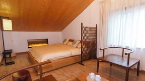A bedroom with a bed, a wooden chair, a bedside table with cups, and a fireplace. - Hangzhou Xuanzhe Homestay (Xihu Scenic Area Meijiawu) (Hangzhou)