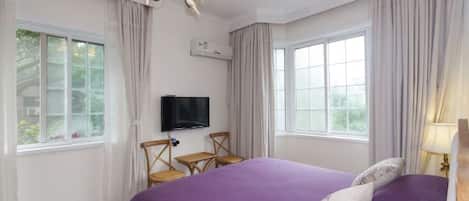 Un dormitorio con una cama grande, televisión, una mesita y dos sillas.