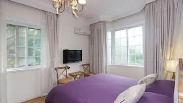 A bedroom with a large bed, a television, and two chairs.