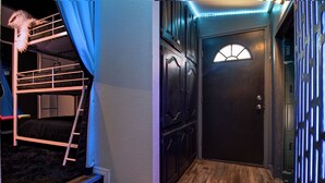 Une pièce avec un lit superposé, une porte avec une fenêtre et un mur décoré de motifs.