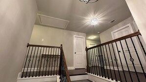 A staircase with a wooden handrail and black balusters, leading to a landing with a white door labeled "Laundry."