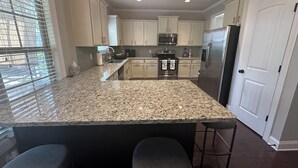 A modern kitchen with granite countertops, stainless steel appliances, and a central island with bar stools.