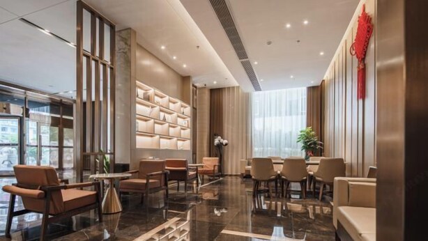 A modern hotel lobby with a seating area, a decorative wall, and a large window. - Wellton City Hotel (Ganzhou Railway Station) (Ganzhou)