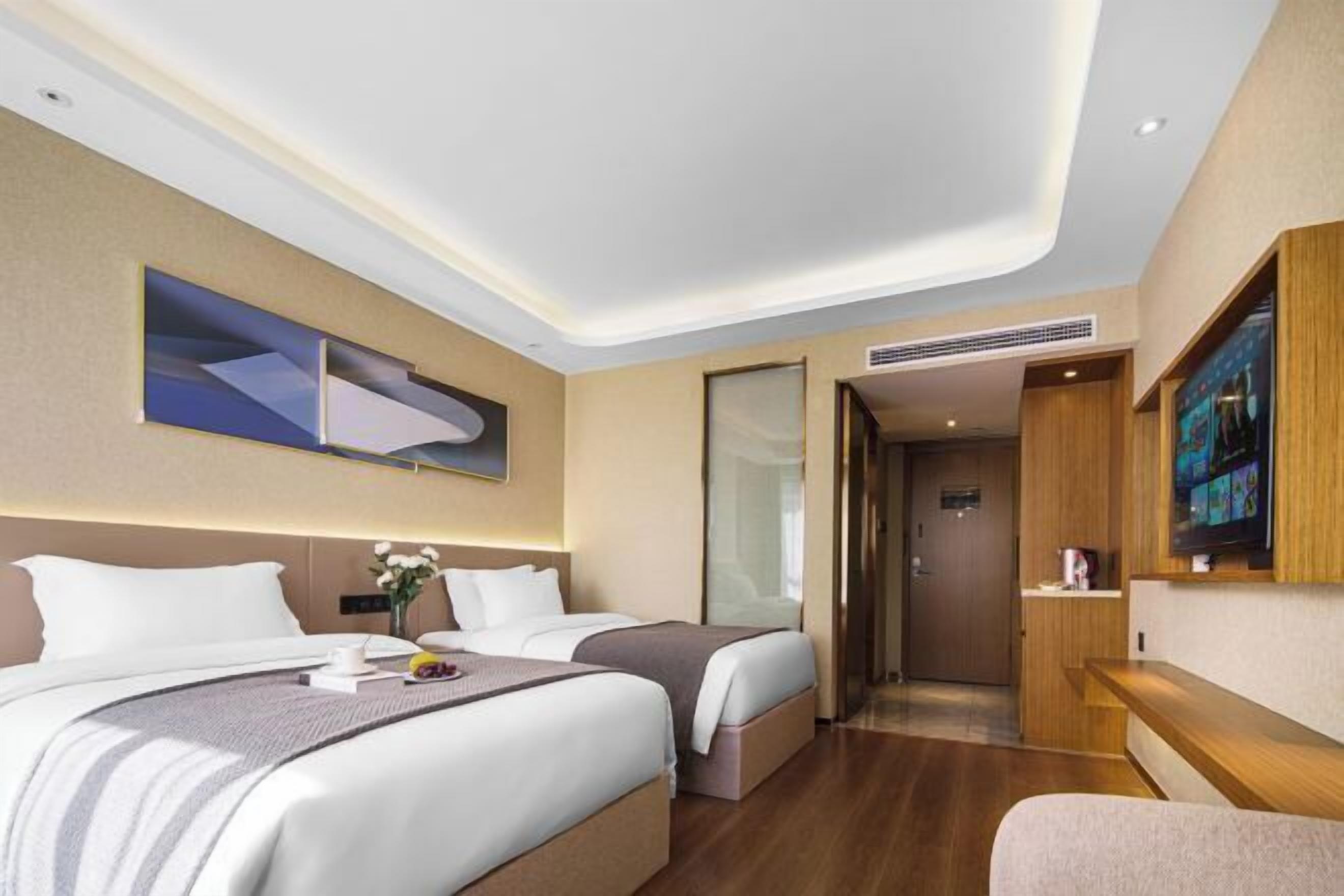 Ett hotellrum med två sängar, en platt-TV, ett skrivbord i trä och ett stort fönster.