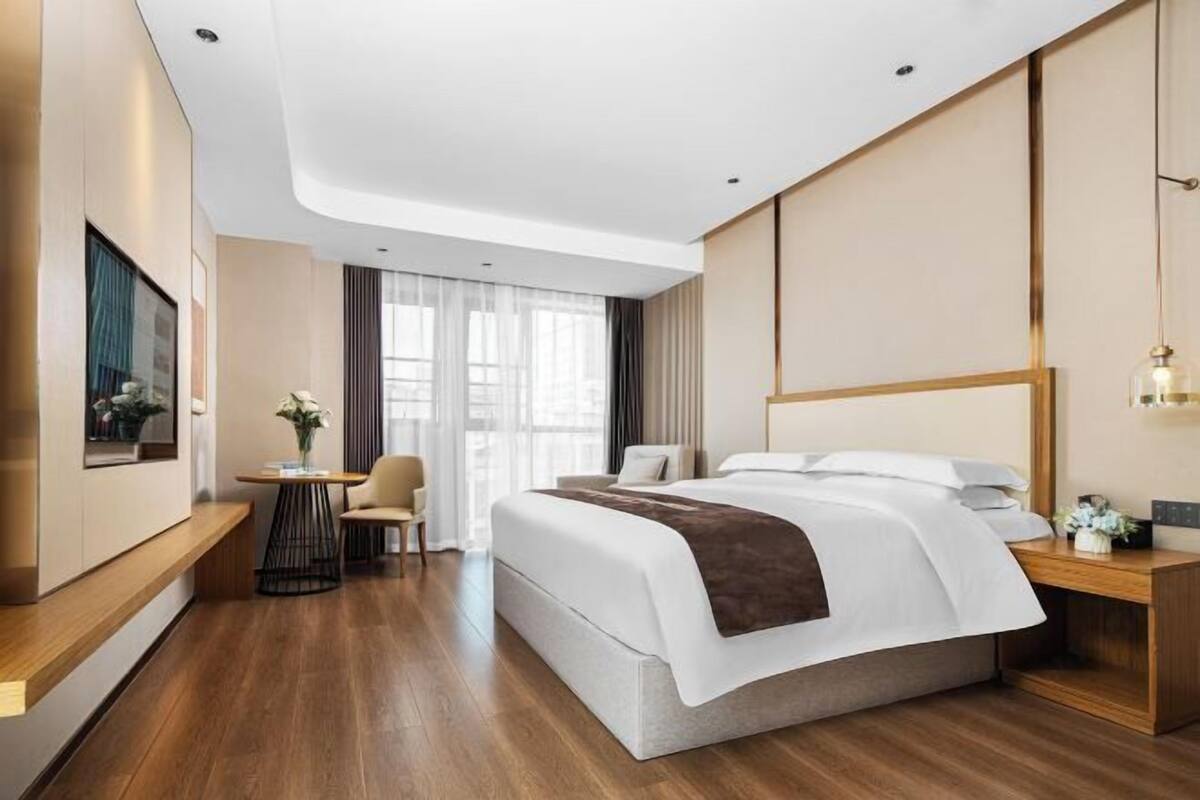 Een moderne hotelkamer met een groot bed, een bureau, een stoel en een televisie.