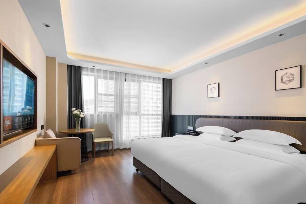 Een moderne hotelkamer met een groot bed, een zithoek en een televisie.