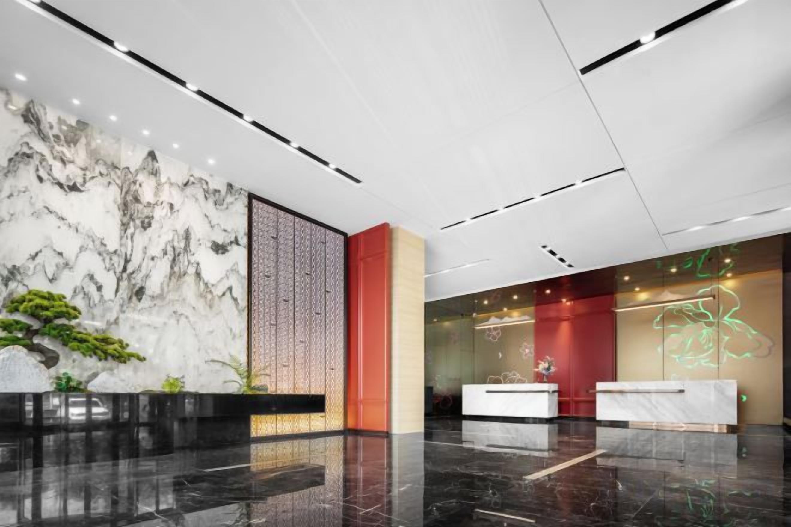 A modern lobby with a marble wall, reception desk, and a decorative light installation.