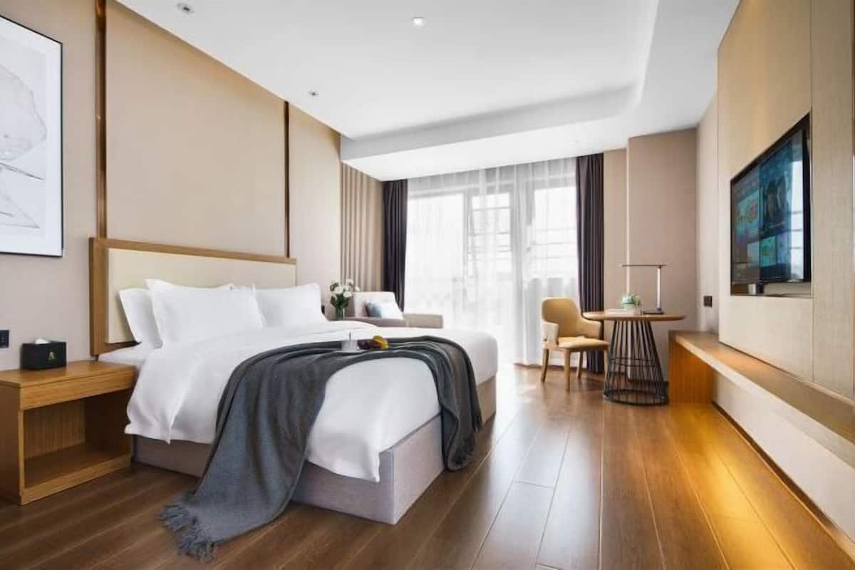 Een moderne hotelkamer met een bed, nachtkastje, stoel en een televisie.