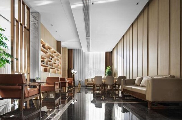 Un hall d’hôtel moderne avec une table basse en verre, des canapés en cuir et une bibliothèque intégrée.