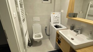 Un baño moderno con inodoro, bidé, lavamanos y espejo.