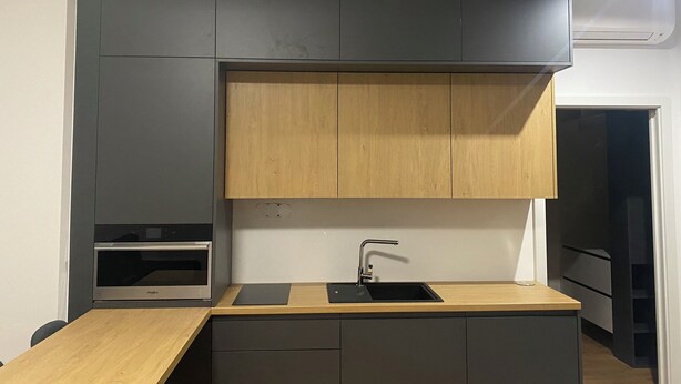 Cocina compacta con horno integrado, pileta y encimera de madera.