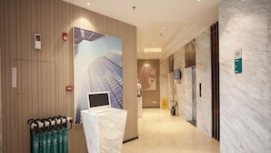 A modern hotel lobby with a reception desk, a digital screen, and a wall-mounted artwork. - Queen Design Hotel (Qiandeng Lake Resort Guicheng Subway Station Branch) (Foshan)