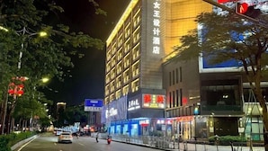A multi-story hotel with illuminated signage, a visible entrance, and a street view with vehicles and trees. - Queen Design Hotel (Qiandeng Lake Resort Guicheng Subway Station Branch) (Foshan)
