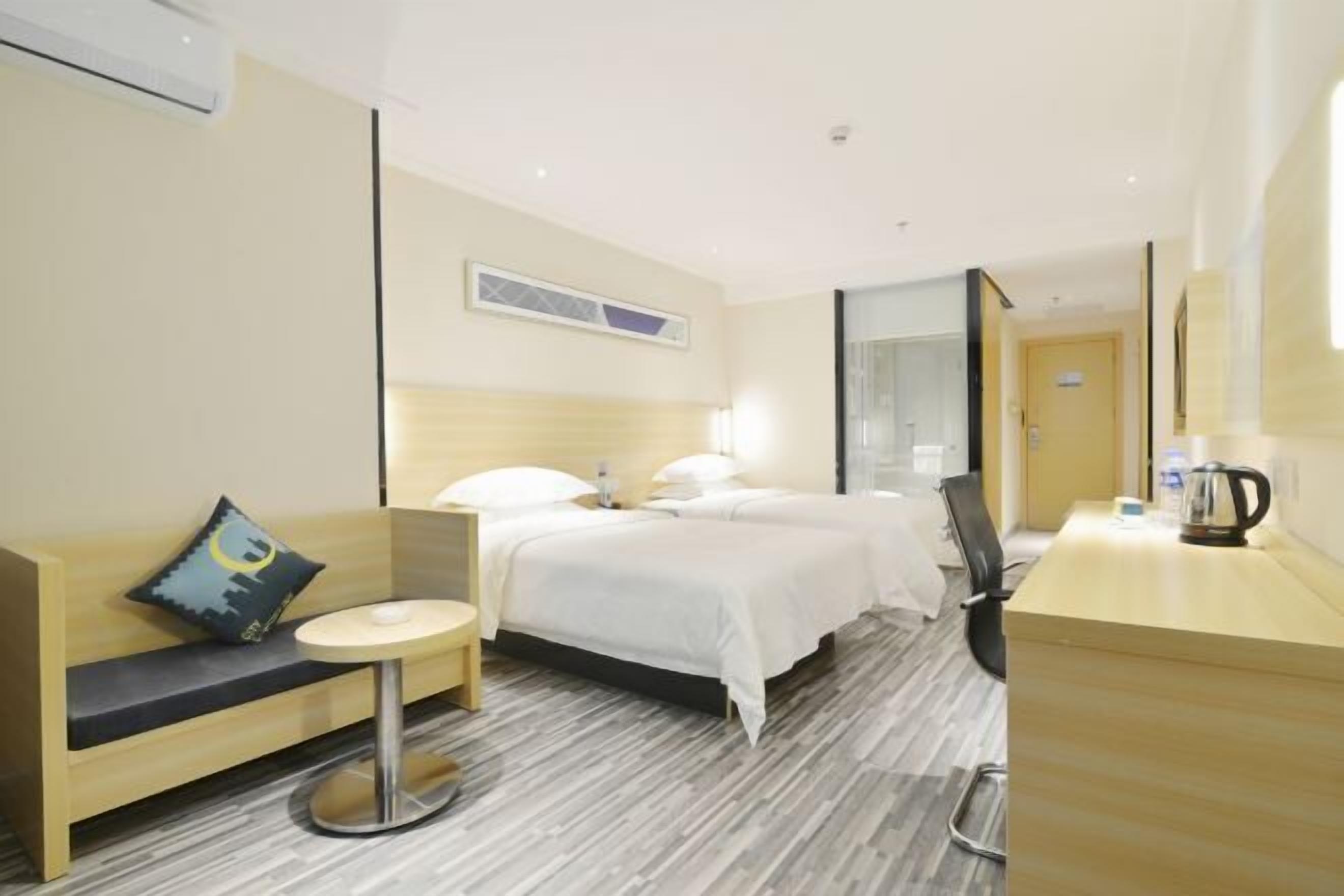 A hotel room with a bed, a desk, a chair, a round table, and a sofa.