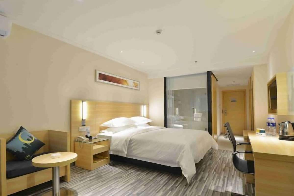 A hotel room with a bed, a desk, a chair, a small table, and a sofa.