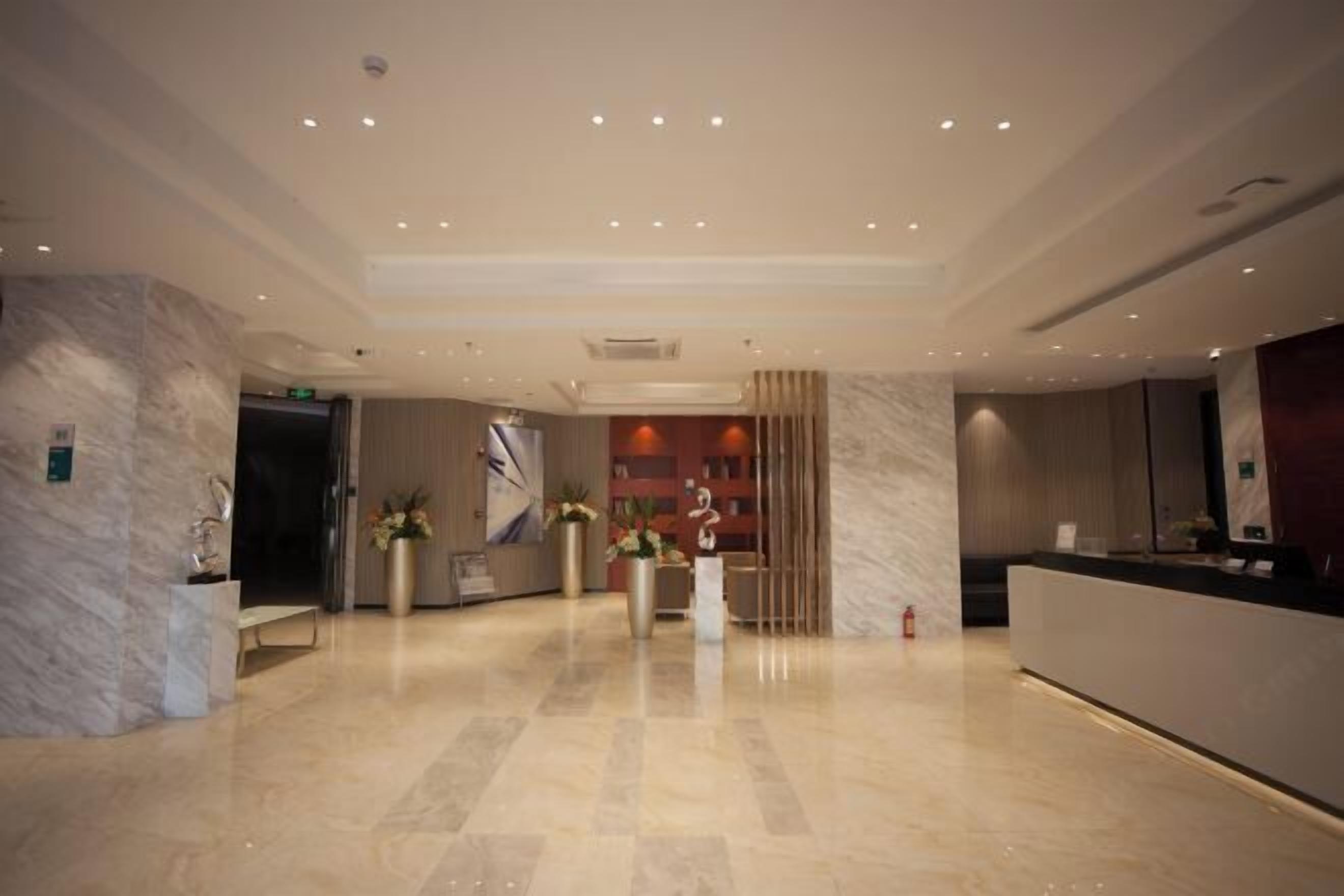A modern hotel lobby with marble flooring, a reception desk, and a fire extinguisher.