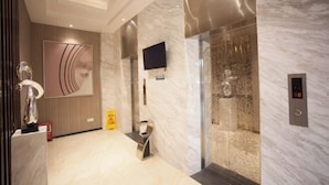 A modern elevator with a digital display, marble walls, and a glass enclosure. - Queen Design Hotel (Qiandeng Lake Resort Guicheng Subway Station Branch) (Foshan)