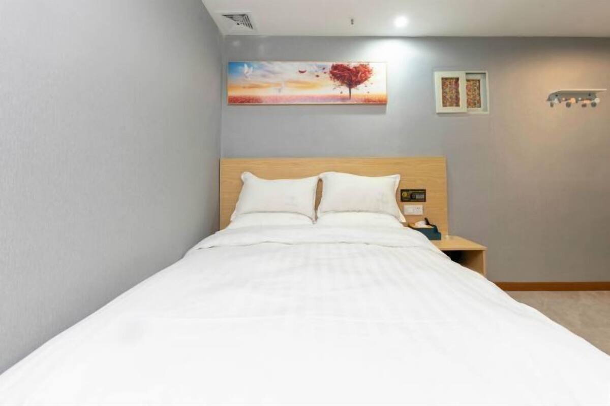 Een net opgemaakt bed met witte lakens in een hotelkamer.