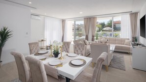 A modern dining area with a white table set for four, surrounded by beige upholstered chairs. - Luxurious home in Vrvari with swimming pool (Vrvari)