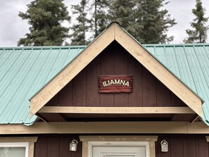 A building with a triangular roof and a wooden sign that reads 'LIAMNA'.