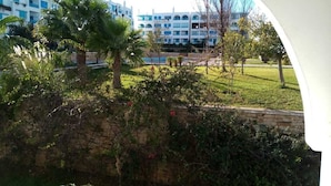 A view of a hotel with a pool and lush greenery. - Family spacious apartment with sea view, AC, WiFi, 7 mins walking to the beach (M'diq)
