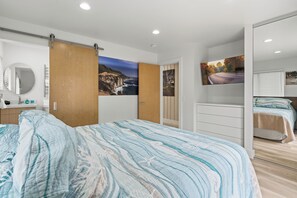 A bedroom with a large bed, a wardrobe, and a painting of a landscape. - Gorgeous hillside home with ocean views! (Moss Beach)