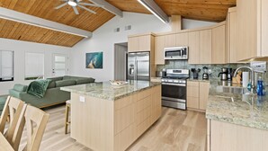 Een moderne keuken met houten kastjes, een centraal eiland, roestvrijstalen apparatuur en een plafondventilator.