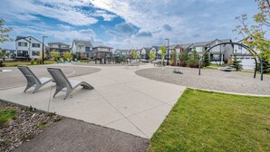 A residential area with houses, a paved courtyard, and benches. - 1 KING Modern Two Bedroom Secondary Suite in Airdrie Alberta (Airdrie)