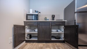 A compact kitchen with dark wood cabinets, a microwave, a stainless steel refrigerator, and a coffee maker. - 1 KING Modern Two Bedroom Secondary Suite in Airdrie Alberta (Airdrie)