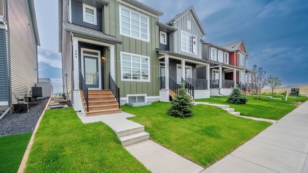A row of modern townhouses with a front porch, a small front yard, and a clear sky. - 1 KING Modern Two Bedroom Secondary Suite in Airdrie Alberta (Airdrie)