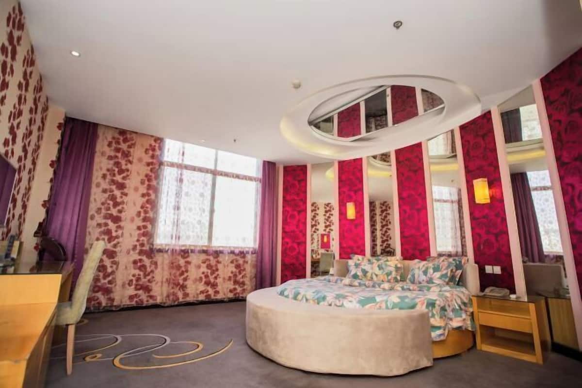 Een slaapkamer met een rond bed, een bureau en een stoel.