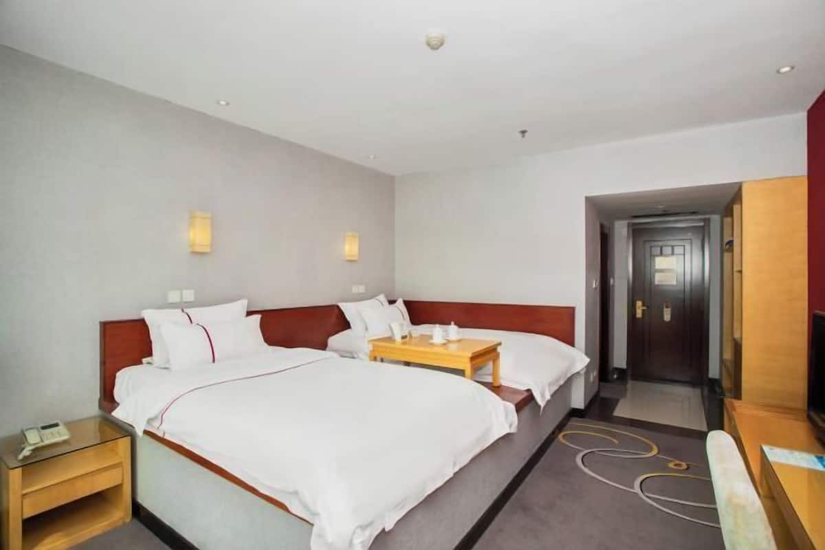 Een hotelkamer met twee bedden, nachtkastjes, een bureau en een kledingkast.