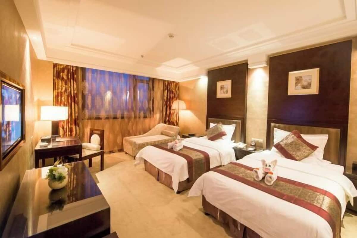 Ein Hotelzimmer mit zwei Betten, einem Schreibtisch, einem Stuhl und einem Fernseher.