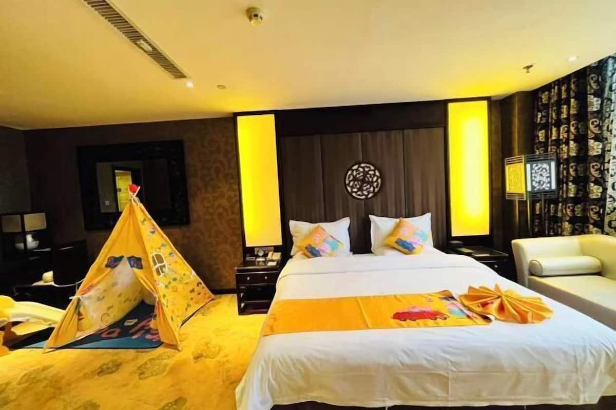 Ein Hotelzimmer mit Bett, Sessel, Nachttisch, Lampe und einem Wanddekor.