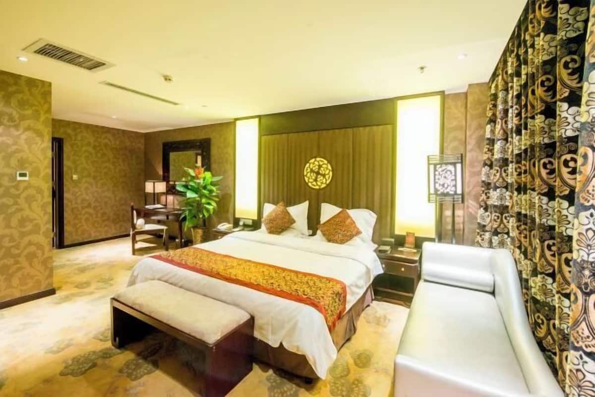 Ein Hotelzimmer mit Bett, einer Bank, einem Schreibtisch und einem Stuhl.