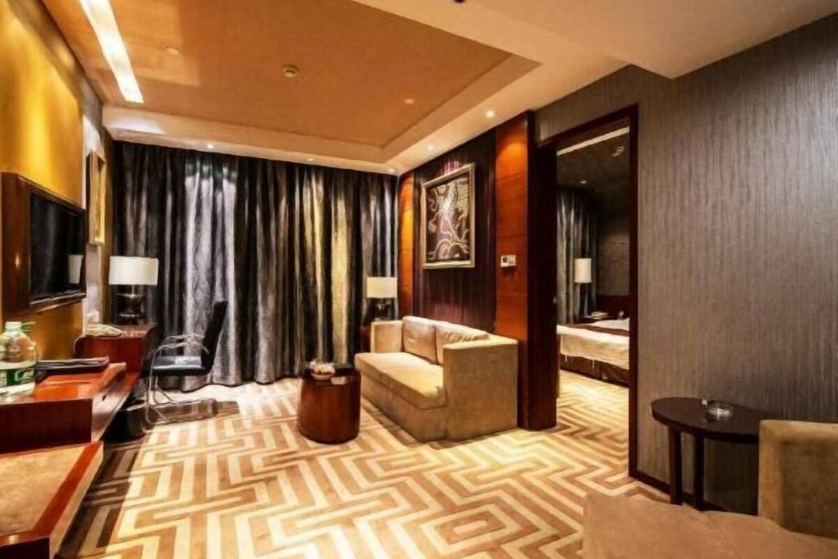 Ein Hotelzimmer mit einer Couch, einem Schreibtisch, einem Sessel, einem Bett und einem Spiegel.
