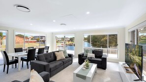 Relax in this stylish living room with a large sofa, flat-screen TV, and dining area.