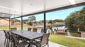 A spacious outdoor dining area with a view of a lake and surrounding houses.