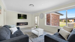 A modern living room with a fireplace, two grey sofas, a coffee table, and a large window with a brick wall view.
