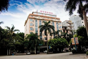 A hotel with multiple floors, a prominent entrance, and a surrounding area with trees and parked cars. - Fuhua Hotel (Dongxing Port) (Dongxing)