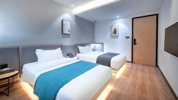 A hotel room with two beds, a desk, and a door.