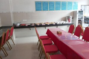Un comedor con una mesa larga, sillas rojas y un mostrador de buffet con alimentos.