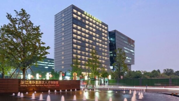 A modern hotel with multiple floors, a water feature in front, and a sign indicating it is the Zhejiang Overseas High-Low Taishan Inn. - The Mulian Hotel of Hangzhou Future Sci-Tech City (Hangzhou)
