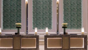 A reception area with a marble counter, two lamps, and a floral arrangement. - The Mulian Hotel (Hangzhou Future Science Town Alibaba Xixi Campus) (Hangzhou)